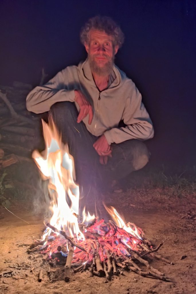 Artist Kenny Martin with a campfire made using friction firelighting