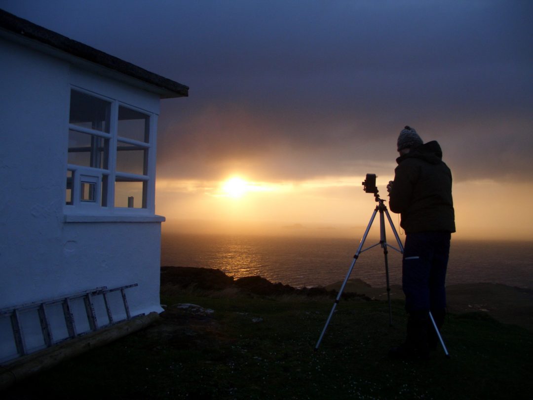 Kenny Martin photographing the sun melting into the ocean off the north coast of the Isle of Skye Scotland